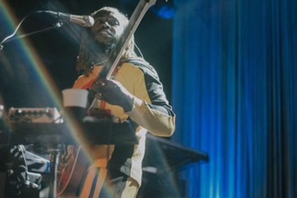 Thundercat performs into a microphone.