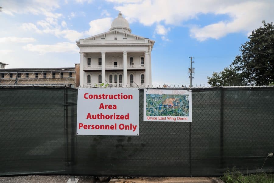 A photo of Bryce Hall behind a fence with construction signs posted. Construction area authorized personnel only. Bryce East Wing demo.