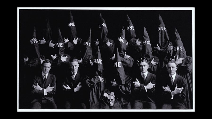A photo of 16 men in black robes and hoods reminiscent of the Ku Klux Klan, embroidered with Theta Nu Epsilon, the official name of The Machine.