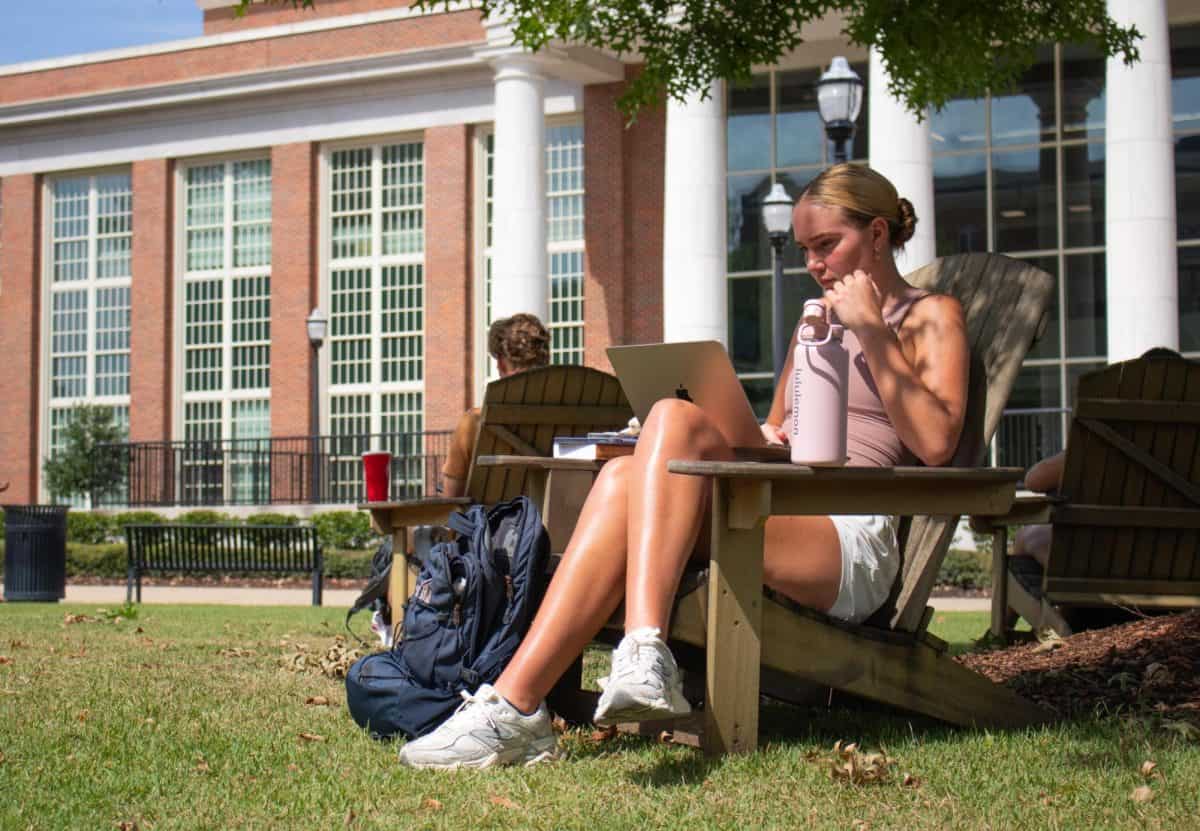 A student studies outside on the Student Center Lawn.
