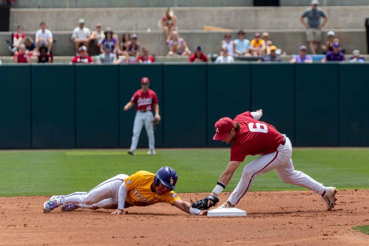 Alabama infielder Max Grant attempts to tag a runner from LSU out.