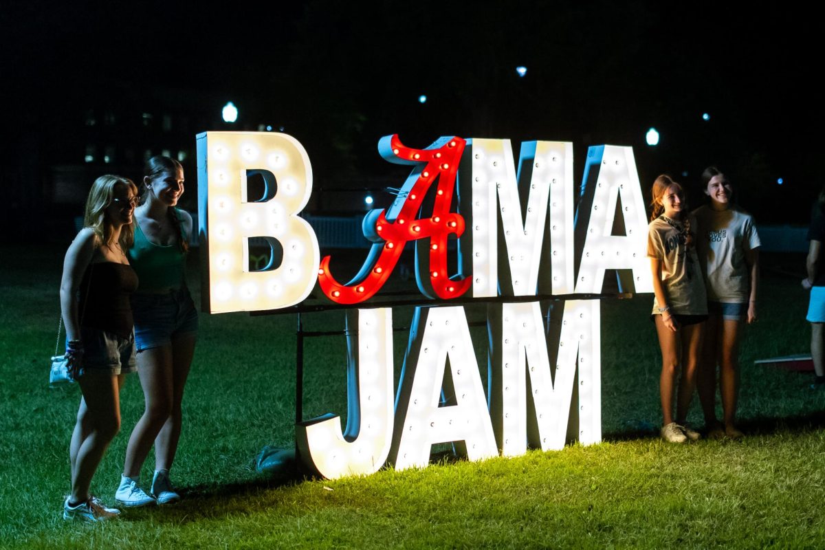 Students pose for a photo next to a Bama Jam sign.