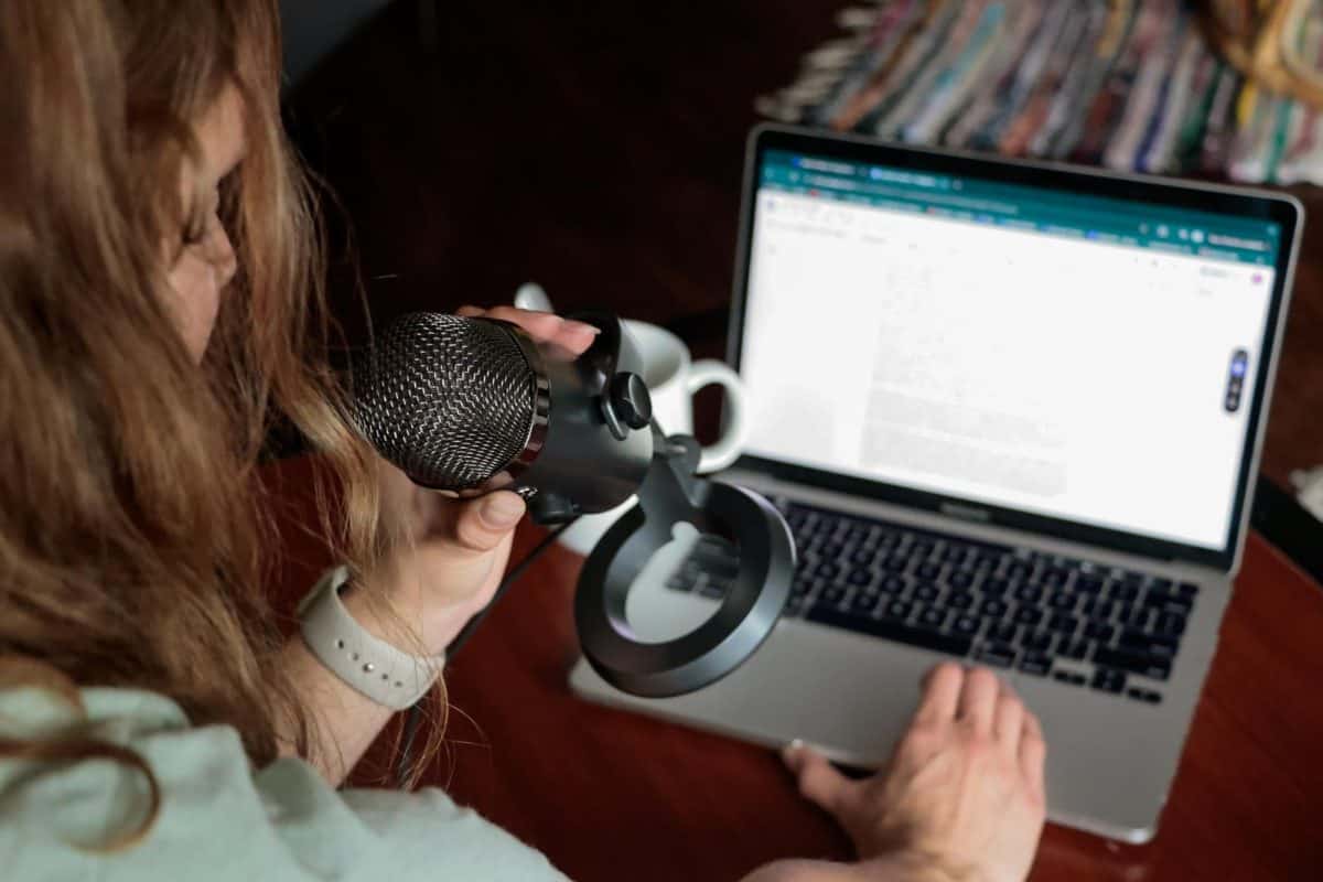 A student sits at their computer with a microphone.