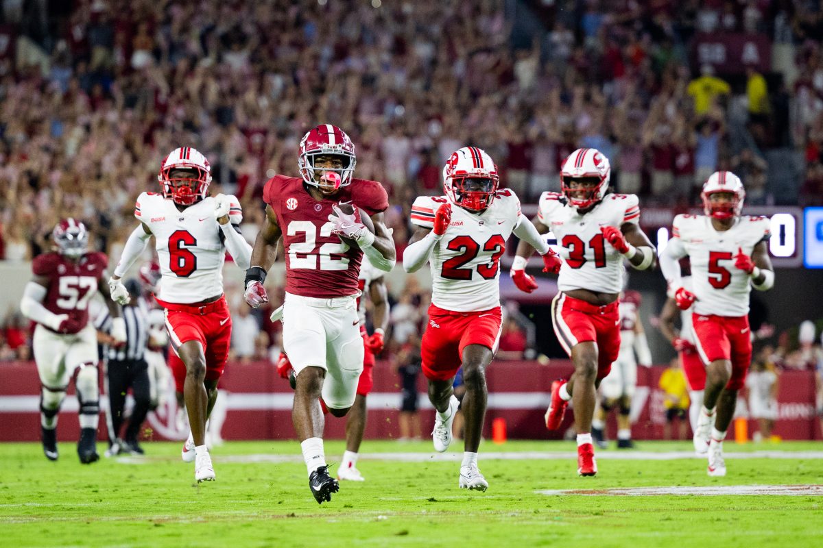 Alabama running back Justice Haynes (#22) runs down the field from Western Kentucky defenders.