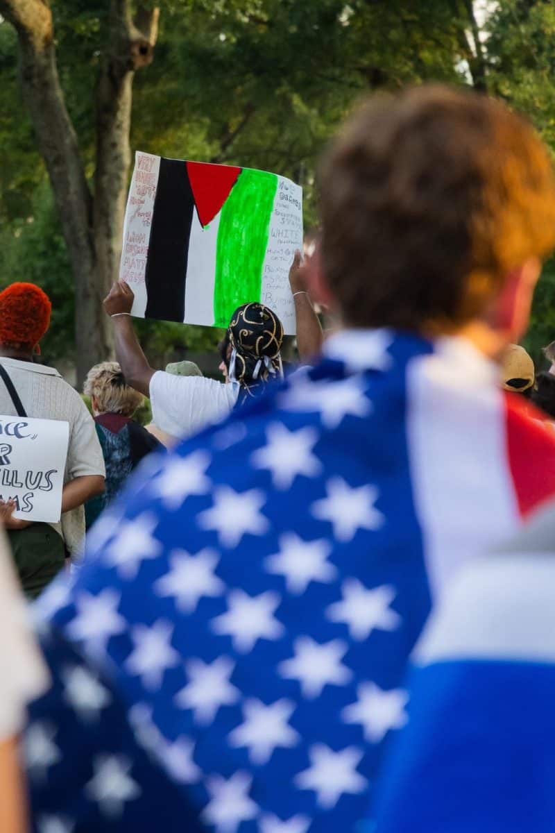 A student raises a pro-Palestine poster as a counterprotester looks on.