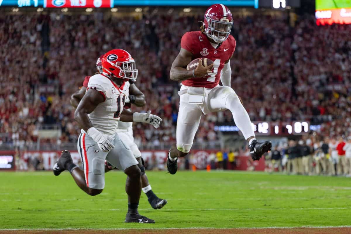 Alabama quarterback Jalen Milroe (#4) jumps into the end zone as a Georgia defender chases on.