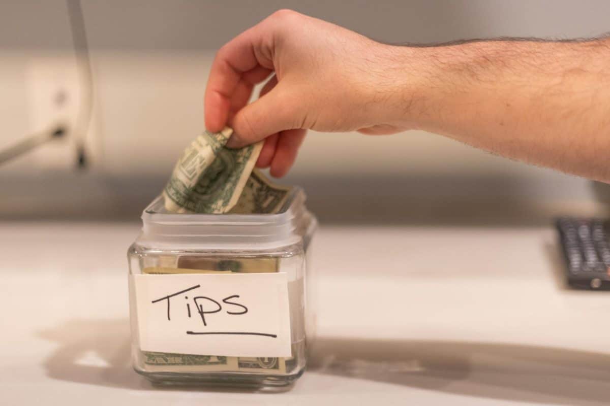 A student places a dollar bill into a tip jar.