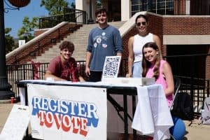 Students sit at a voter registration table.