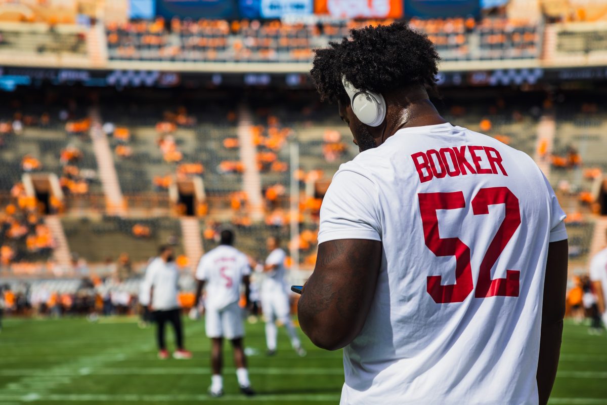 Alabama offensive lineman Tyler Booker (#52) looks down at his phone.