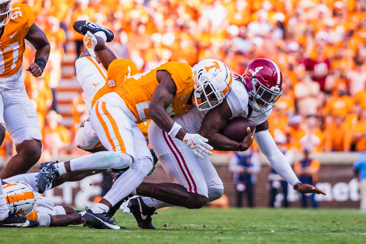 Alabama quarterback Jalen Milroe (#4) is tackled by a Tennessee defender.