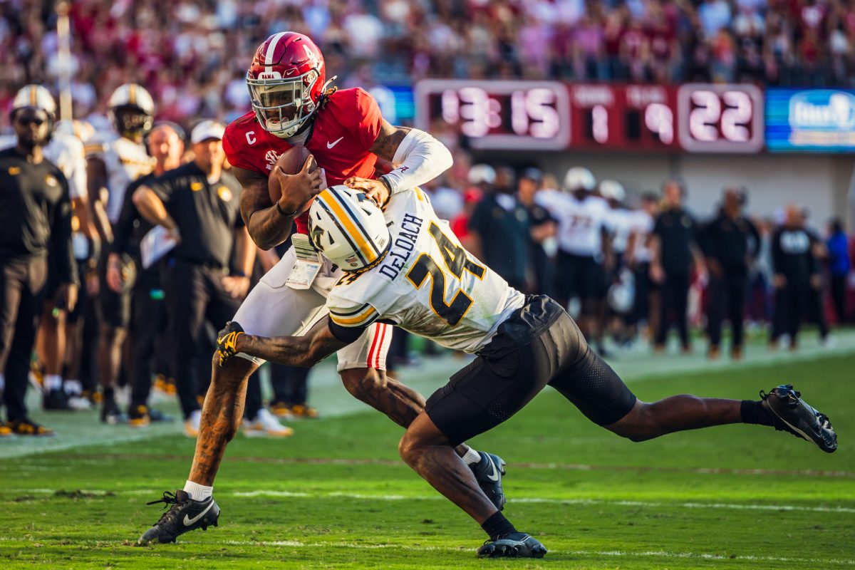 Alabama quarterback Jalen Milroe (#24) pushes a Missouri defender away.