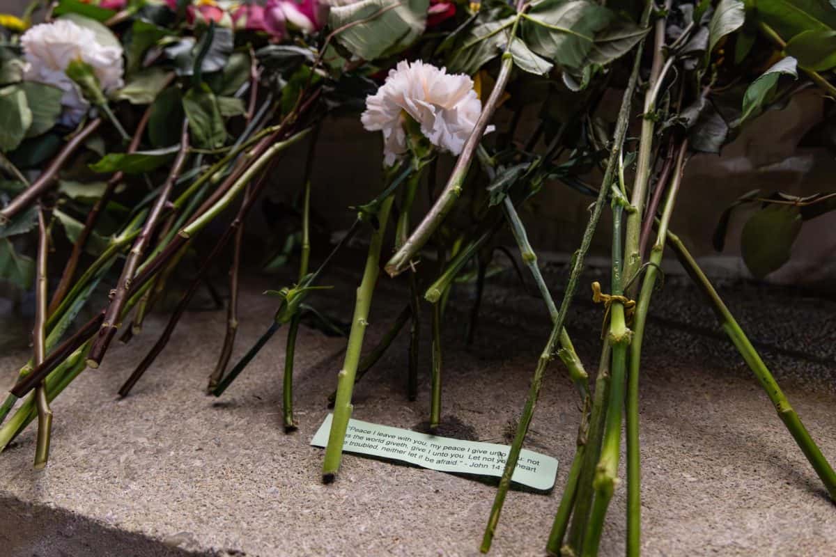 Alabama student lay Bible verse by flowers at prayer vigil for Kirk. 