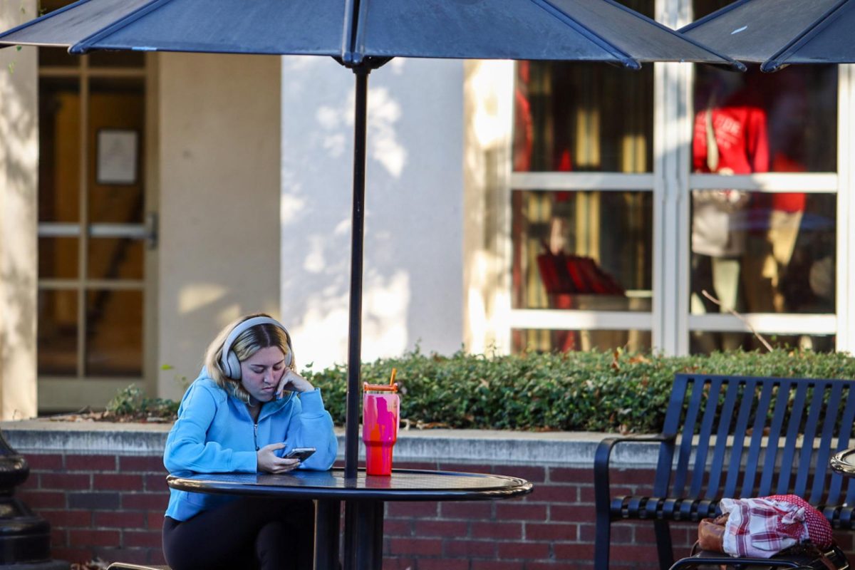 Student plays on their phone outside the Student Center. 