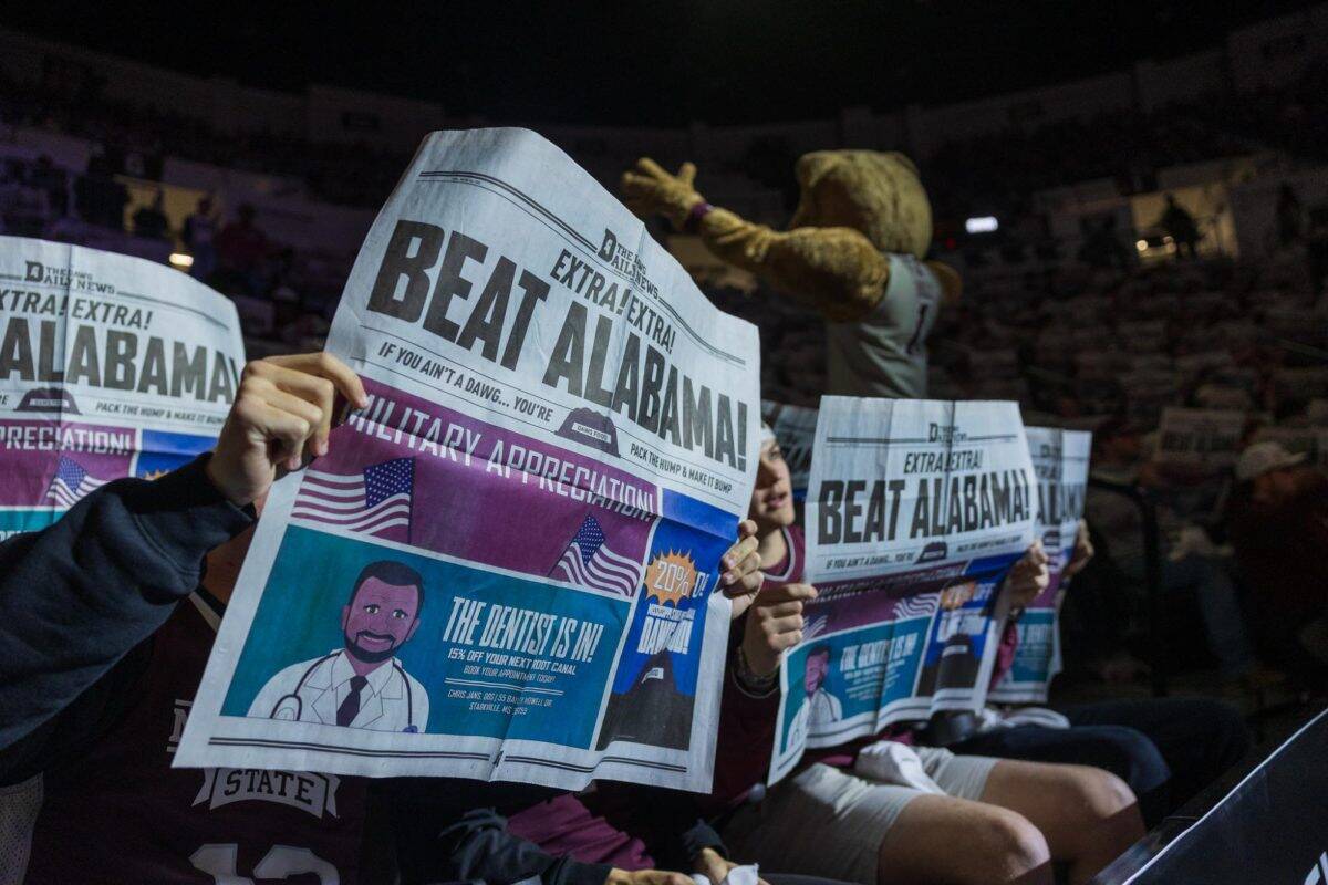 Mississippi State students hold up newspapers before playing Alabama.